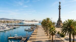 Port Vell harbour promenade in Barcelona with a cruise ship in the distance